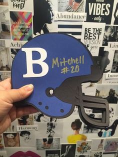 a hand holding up a football helmet with the letter b on it's side