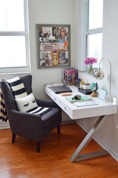 a desk with a chair and pictures on the wall behind it in front of a window