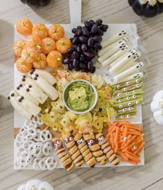 a platter with crackers, grapes, carrots, cheese sticks and other snacks