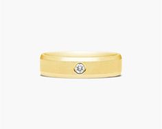 a yellow gold wedding band with a diamond in the center and a beveled edge