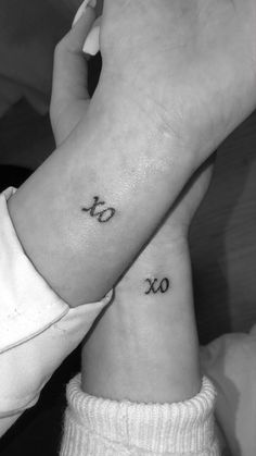 two people holding hands with tattoos on their wrists and one has the word love written in cursive letters