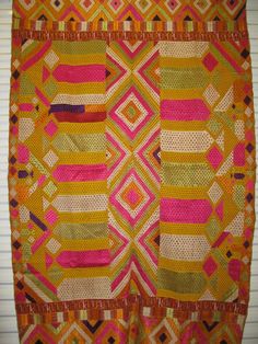 an orange and pink quilt hanging on a wall