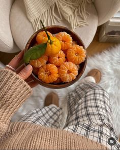 a person holding a bowl filled with oranges