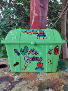 a green lunch box sitting on top of a wooden table next to a red pole