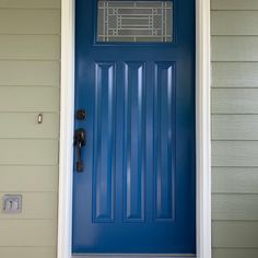 a blue front door on a house with two sidelights and a window above it