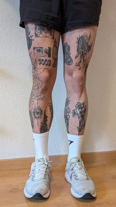 the legs and ankles of a man with tattoos on his body, wearing tennis shoes