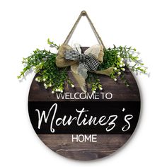 a welcome sign hanging from the side of a wooden wall with a bow on it