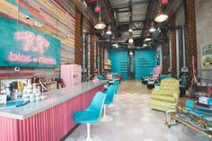 the inside of a hair salon with colorful chairs and lights on it's walls