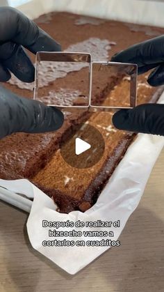 two hands in black gloves are touching a chocolate cake