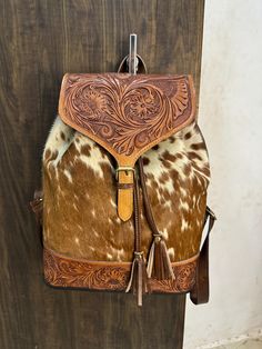 Dimensions: 16" (Height) x 16.5" (Width) x 5" (Depth) -Premium Leather -Hand Tooled Leather -Adjustable Leather Strap -Rucksack Closure -Pocket Inside -Leather Handbag Dimensions: 16"x 16.5"x 5" Western Style Hand-tooled Travel Bag, Brown Hand Tooled Bag For Rodeo, Western Hand Tooled Travel Bag, Hand Tooled Brown Bag For Rodeo, Hand Tooled Brown Bags For Rodeo, Rucksack Bag, Leather Leaf, Hand Tooled Leather, Tooled Leather