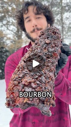 a man holding up a large piece of meat in the snow