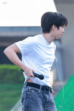 a young man is listening to music with headphones on while standing in front of a skateboard