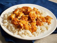 a white plate topped with rice covered in meat and sauce on top of a blue towel