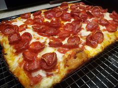 a pepperoni pizza sitting on top of a metal rack