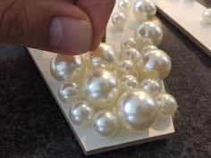 a hand is pointing at some white pearls