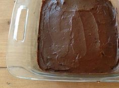 a chocolate cake in a glass dish on a wooden table