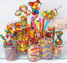 a table topped with lots of candy and lollipops on top of glass containers