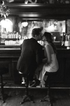 a man and woman kissing in front of a bar