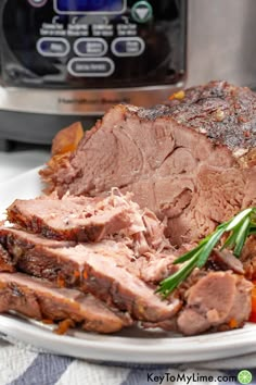 a white plate topped with meat next to an instant pot roaster