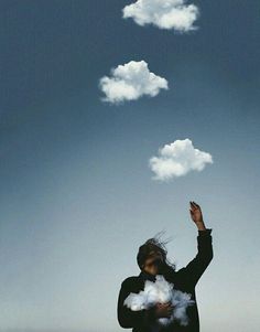 a woman standing in front of a sky with clouds floating from her head and arms