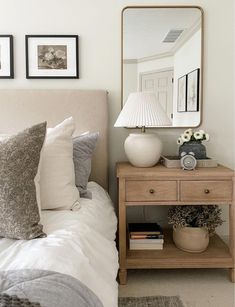 a bedroom with a bed, nightstand and mirror on the wall above it's headboard