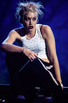 a woman in white shirt and black pants sitting on stage with her hand on the ground