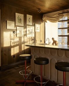 an image of a kitchen setting with barstools and pictures on the wall behind it