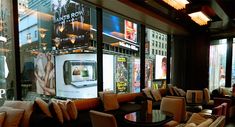 an empty restaurant with couches and tables in front of large windows that have advertisements on them