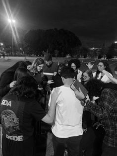 a group of people standing around each other in a park at night with lights on