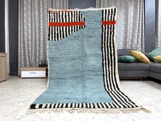 a blue rug with black and white stripes on it in front of a gray couch