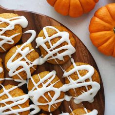 a wooden plate topped with cookies covered in icing next to mini pumpkins and gourds