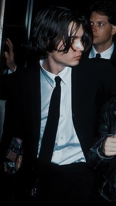 two men in suits and ties are walking through an elevator together, one is wearing a black jacket