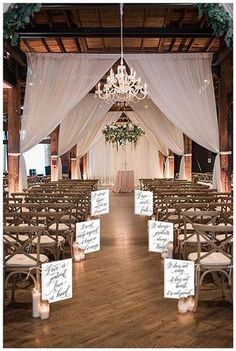 an indoor wedding venue with white drapes and chandelier hanging from the ceiling