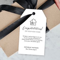 a gift wrapped in brown paper with a black ribbon and tag that says congratulations on your new home