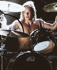 a man with no shirt on playing drums