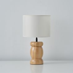 a small wooden table lamp with a white shade on the top and bottom part of it