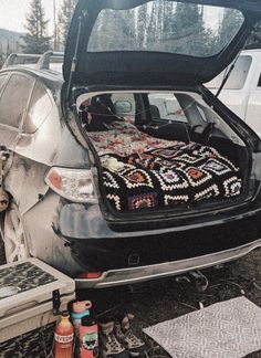 the back end of a car with an open trunk filled with blankets and other items