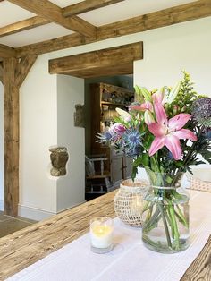 a vase filled with flowers sitting on top of a wooden table next to a candle