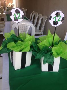 two black and white gift boxes with green tissue paper on them, decorated with soccer balls