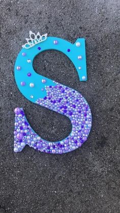 the letter s is made out of blue and purple beads with a crown on top