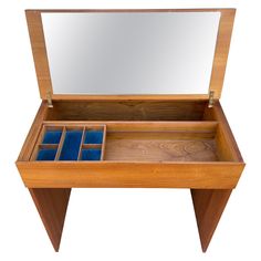 an open wooden box with blue velvet linings on the bottom and inside, sitting in front of a mirror