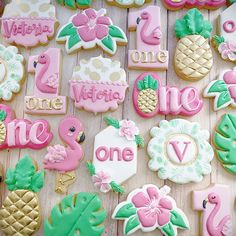 decorated cookies are arranged on a table with flowers and pineapples in the background