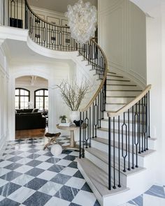 an elegant foyer with black and white checkered flooring, chandelier and staircase