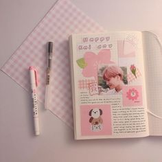 an open book with pictures on it and a pen next to it, sitting on top of a pink checkered table cloth