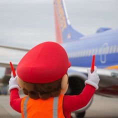 a person in an orange safety vest standing next to a plane