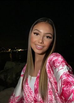 a woman with long hair wearing a pink and white kimono posing for a photo