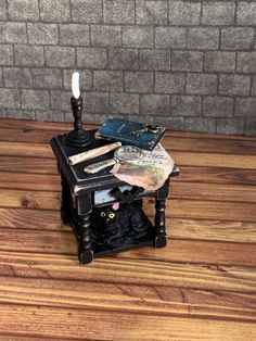 a small black table with books and a lamp on it, sitting in front of a brick wall