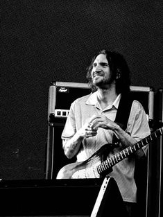 a man with long hair playing an electric guitar