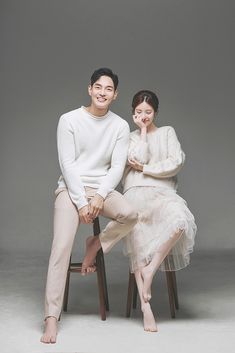 two people sitting on stools posing for the camera