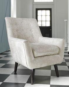 a white chair sitting on top of a black and white checkered floor next to a doorway